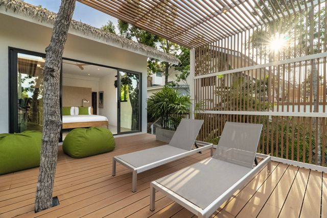 Sunlight through a timber pergola over lounge chairs beside a pool at a Pahili villa